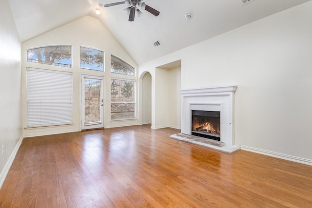 7108 Sugarplum Dr, Plano, TX 75074 - unfurnished living room with a ceiling fan, arched walkways, a warm lit fireplace, wood finished floors, and vaulted ceiling
