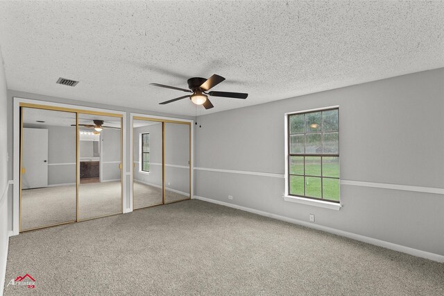 5630 Shreveport Blanchard Hwy, Shreveport, LA 71107 - unfurnished bedroom with two closets, carpet floors, a textured ceiling, a ceiling fan, and baseboards