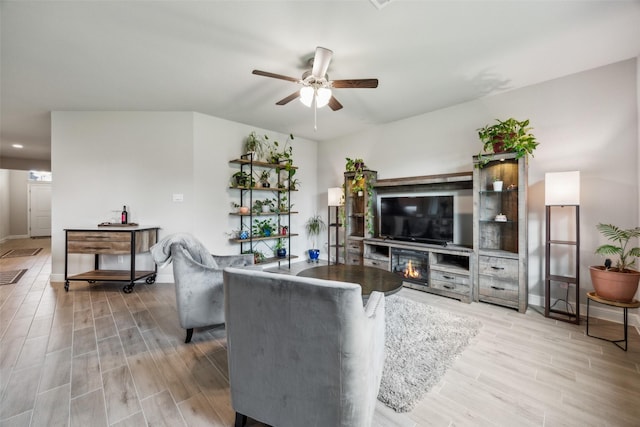 236 Mossy Cliff Ln, Fort Worth, TX 76052 - living room featuring a ceiling fan, light wood-type flooring, baseboards, and a glass covered fireplace