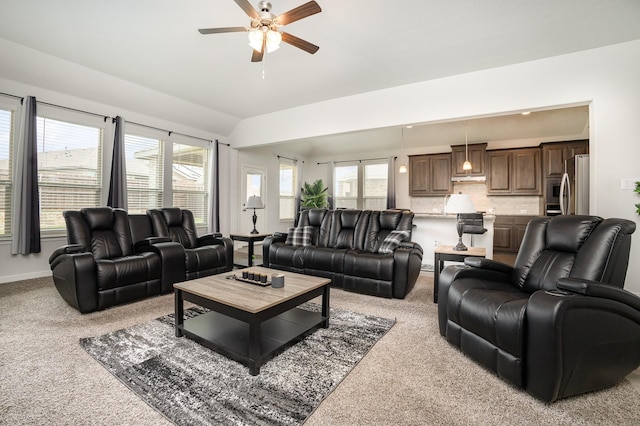 living area featuring light colored carpet, ceiling fan, vaulted ceiling, and baseboards