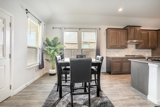 kitchen featuring light wood-type flooring, decorative backsplash, lofted ceiling, recessed lighting, and light stone counters