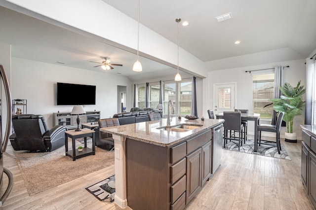 kitchen with a sink, light wood-style flooring, dishwasher, light stone countertops, and healthy amount of natural light
