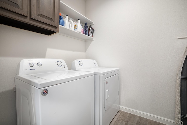 washroom featuring wood finished floors, independent washer and dryer, cabinet space, and baseboards