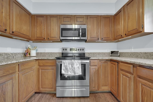 2434 Antler Trl, Lewisville, TX 75067 - kitchen featuring appliances with stainless steel finishes, light wood-type flooring, brown cabinets, and light stone countertops