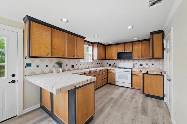304 E Lee Ave, Weatherford, TX 76086 - kitchen featuring white gas stove, a sink, a peninsula, light wood-style floors, and brown cabinets