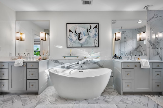 bathroom with marble look tile flooring, vanity, a marble finish shower, a freestanding bath, and tile walls