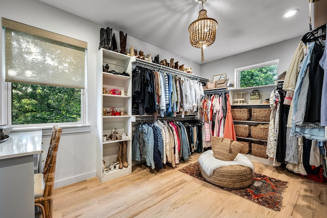 spacious closet with wood finished floors and a chandelier