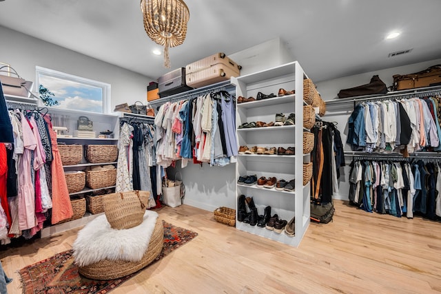 walk in closet featuring wood finished floors and a chandelier