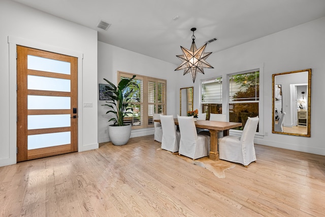 dining area with wood finished floors, healthy amount of natural light, baseboards, and a chandelier