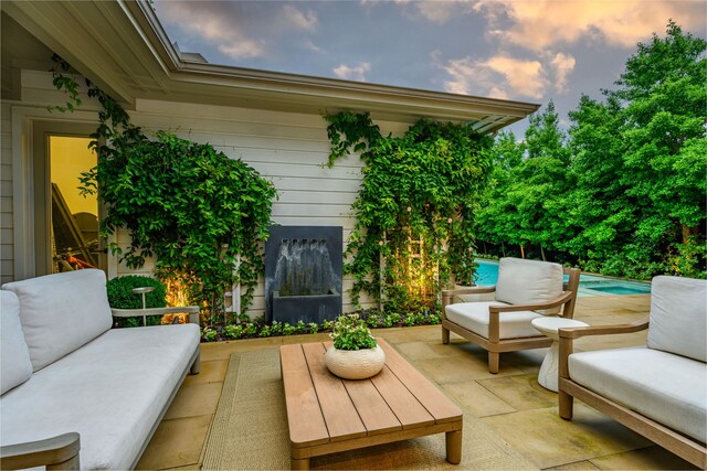 patio terrace at dusk with an outdoor hangout area, a patio, and an outdoor pool