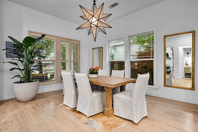 dining room featuring light wood-style flooring, a chandelier, and baseboards