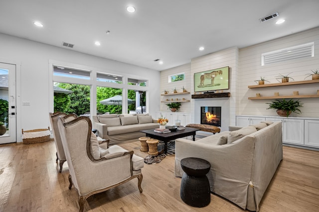living room featuring light wood finished floors, a glass covered fireplace, and recessed lighting