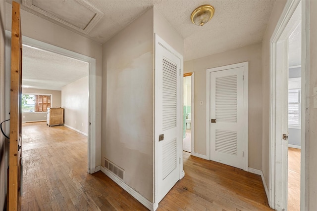 1677 Hobbs Ln, Waco, TX 76706 - hallway featuring a textured ceiling, hardwood / wood-style floors, baseboards, and attic access