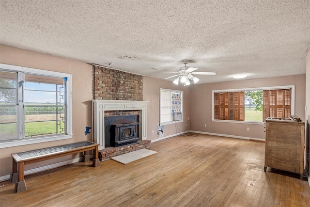 1677 Hobbs Ln, Waco, TX 76706 - unfurnished living room with a wood stove, wood finished floors, a textured ceiling, a ceiling fan, and baseboards