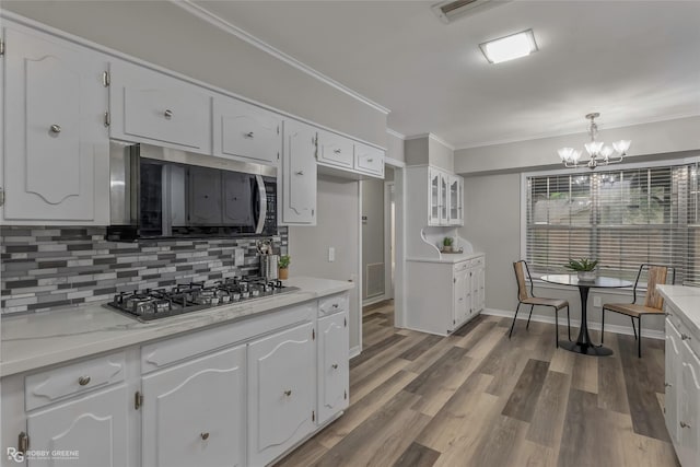 817 S Spruce St, Vivian, LA 71082 - kitchen with stainless steel appliances, white cabinets, backsplash, crown molding, and a chandelier