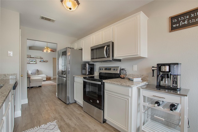 1034 Palomino Dr, Little Elm, TX 75068 - kitchen with appliances with stainless steel finishes, a ceiling fan, light wood-style flooring, white cabinetry, and light stone counters