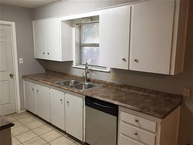 2406 14th Th, Brownwood, TX 76801 - kitchen with stainless steel dishwasher, a sink, white cabinetry, and dark countertops