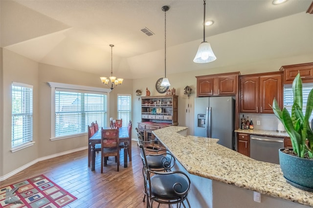 7201 Mcleod Dr, Abilene, TX 79602 - kitchen featuring stainless steel appliances, wood finished floors, a chandelier, light stone countertops, and lofted ceiling