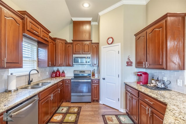 7201 Mcleod Dr, Abilene, TX 79602 - kitchen featuring stainless steel appliances, a sink, crown molding, light wood-style floors, and decorative backsplash