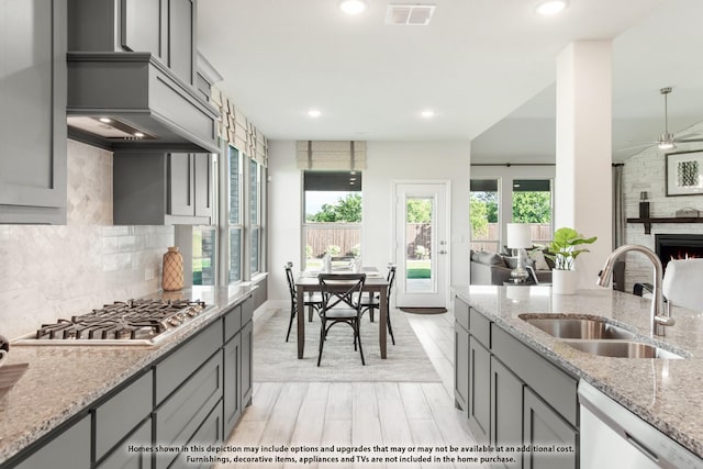 406 Maltese Cir, Wylie, TX 75098 - kitchen with a sink, gray cabinetry, dishwasher, stainless steel gas cooktop, and light stone counters