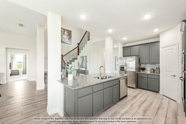 406 Maltese Cir, Wylie, TX 75098 - kitchen with a sink, stainless steel appliances, gray cabinetry, light stone countertops, and light wood-style flooring