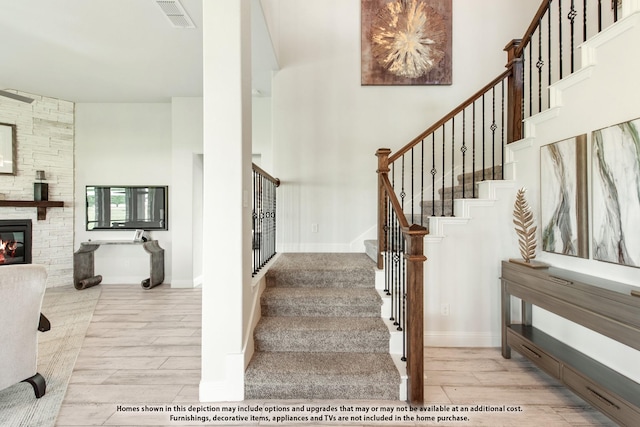 406 Maltese Cir, Wylie, TX 75098 - staircase with wood finished floors, a high ceiling, a stone fireplace, and baseboards