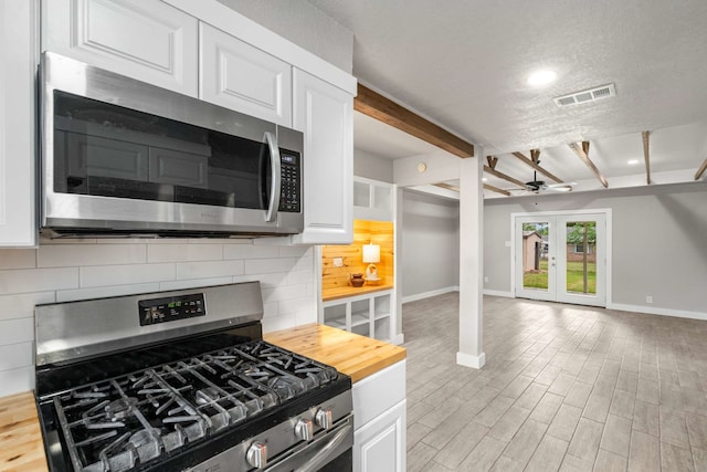 6012 Whispering Ln, Watauga, TX 76148 - kitchen featuring stainless steel appliances, wooden counters, baseboards, open floor plan, and white cabinets