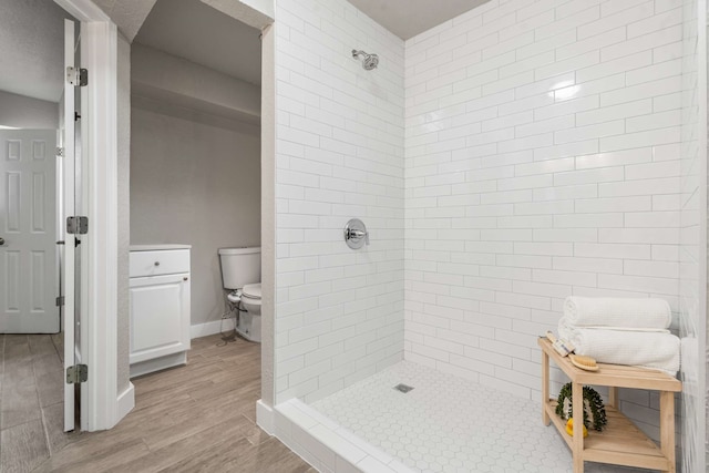 6012 Whispering Ln, Watauga, TX 76148 - full bathroom featuring a tile shower, wood finished floors, toilet, and baseboards