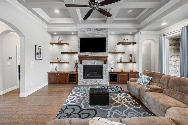 1103 Hilkiah Ct, Granbury, TX 76048 - living room with ceiling fan, light wood-type flooring, arched walkways, coffered ceiling, and a stone fireplace