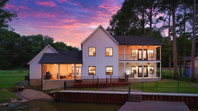 138 Sunset Dr, Gun Barrel City, TX 75156 - back of property at dusk featuring ceiling fan, a balcony, a patio, roof with shingles, and board and batten siding