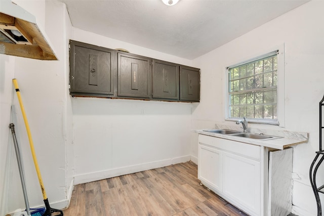 1622 Ave B, Dallas, TX 75203 - laundry room with cabinet space, light wood finished floors, and baseboards