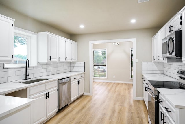 1202 Bayshore Dr, Rockwall, TX 75087 - kitchen featuring appliances with stainless steel finishes, a sink, tasteful backsplash, white cabinetry, and recessed lighting