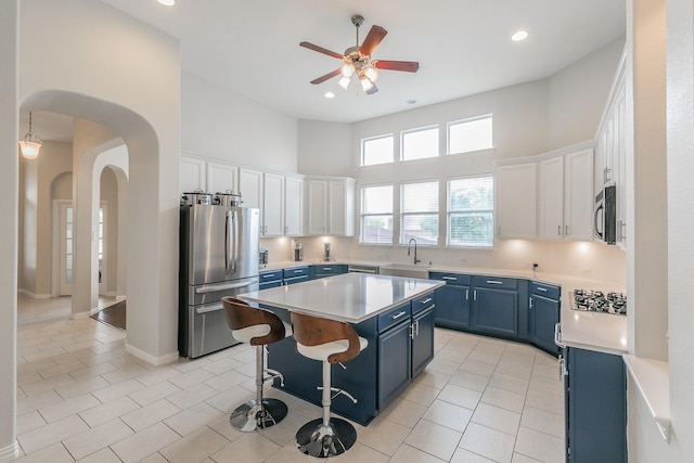 941 Sequoia Way, Saginaw, TX 76131 - kitchen featuring appliances with stainless steel finishes, blue cabinets, arched walkways, a kitchen island, and light countertops