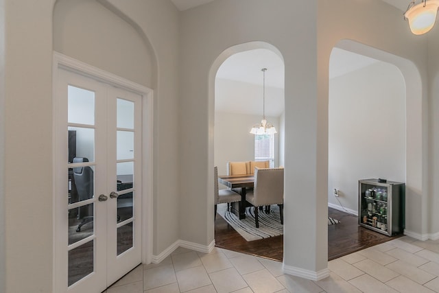 941 Sequoia Way, Saginaw, TX 76131 - hallway featuring french doors, arched walkways, light tile patterned floors, a chandelier, and baseboards