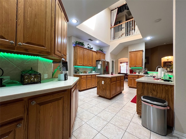 6869 Cape Cod Dr, Grand Prairie, TX 75054 - kitchen featuring light tile patterned flooring, brown cabinetry, stainless steel fridge, and tasteful backsplash