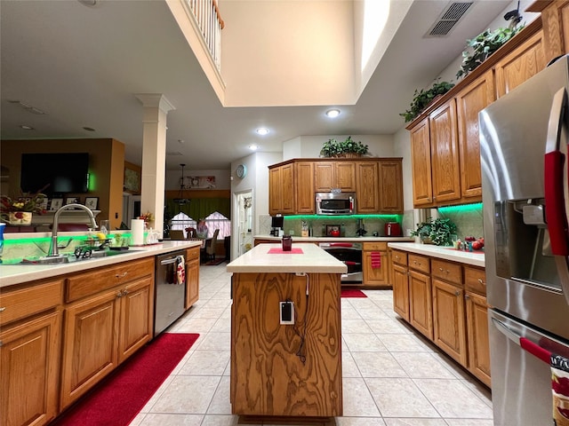 6869 Cape Cod Dr, Grand Prairie, TX 75054 - kitchen featuring appliances with stainless steel finishes, a sink, a kitchen island, light countertops, and brown cabinets