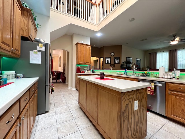 6869 Cape Cod Dr, Grand Prairie, TX 75054 - kitchen with stainless steel appliances, arched walkways, a sink, a kitchen island, and light tile patterned flooring