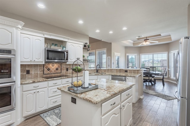 1777 Lone Star Blvd, Terrell, TX 75160 - kitchen featuring appliances with stainless steel finishes, a tray ceiling, a peninsula, a sink, and open shelves