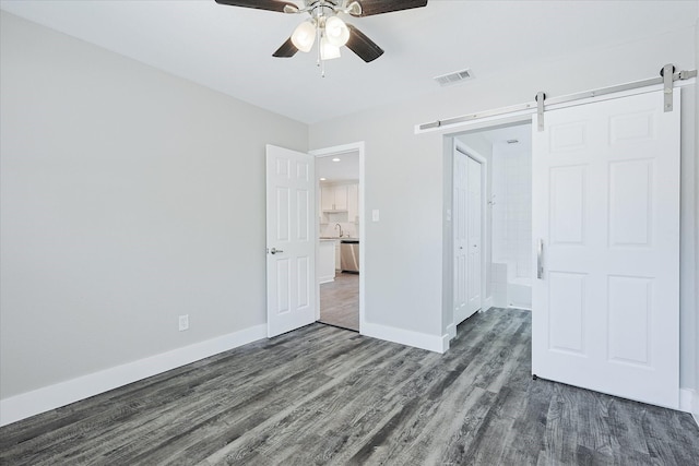 821 Collin Dr, Euless, TX 76039 - unfurnished bedroom with a barn door, dark wood-style flooring, baseboards, ceiling fan, and a sink