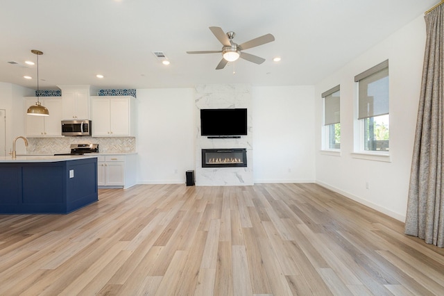 913 Emerling Dr, Mckinney, TX 75069 - unfurnished living room featuring light wood finished floors, a ceiling fan, a premium fireplace, recessed lighting, and baseboards
