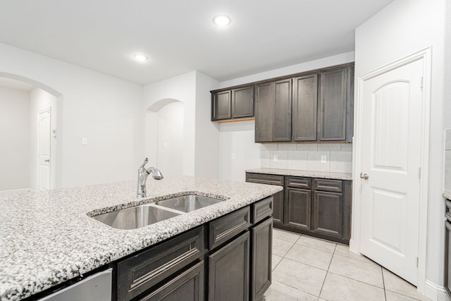 1211 Templin Ave, Forney, TX 75126 - kitchen featuring a sink, arched walkways, light stone counters, dark brown cabinets, and recessed lighting