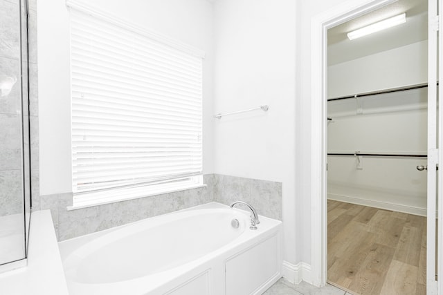 1211 Templin Ave, Forney, TX 75126 - bathroom with a bath, a spacious closet, wood finished floors, and a shower