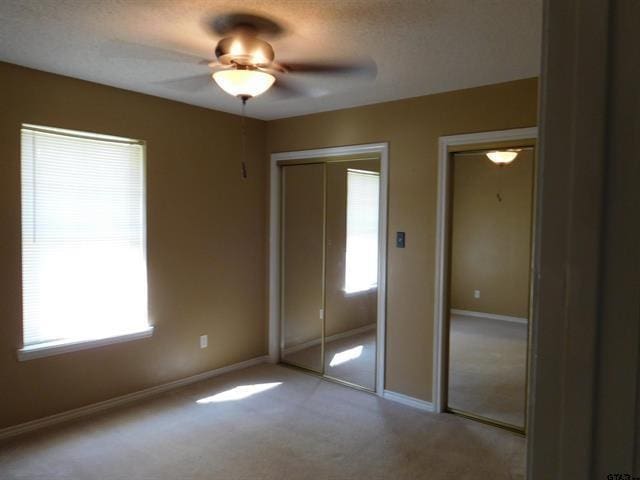 405 Cherry St, Chandler, TX 75758 - unfurnished bedroom featuring multiple windows, carpet flooring, two closets, and baseboards