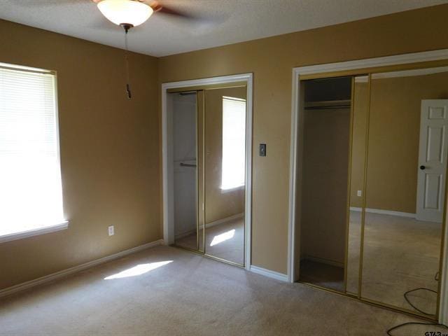 405 Cherry St, Chandler, TX 75758 - unfurnished bedroom with multiple closets, light carpet, baseboards, and ceiling fan