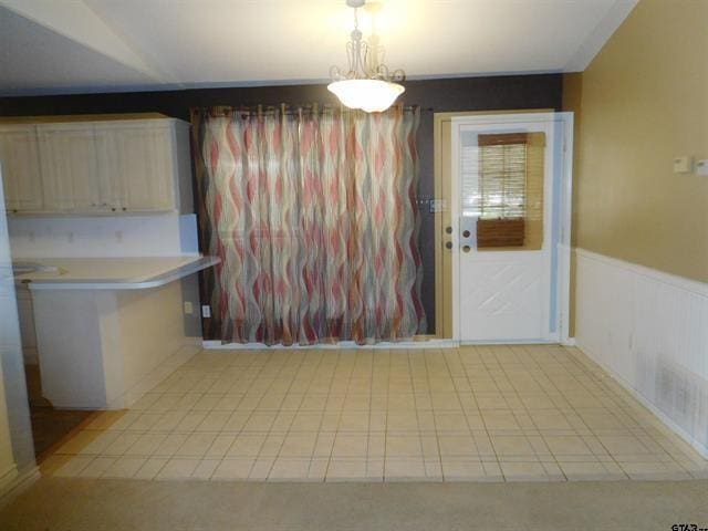 405 Cherry St, Chandler, TX 75758 - unfurnished dining area with a wainscoted wall and light tile patterned flooring