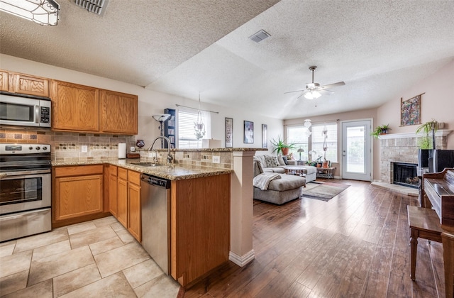 1312 Dakota Trl, Krum, TX 76249 - kitchen featuring appliances with stainless steel finishes, a sink, open floor plan, a peninsula, and a ceiling fan
