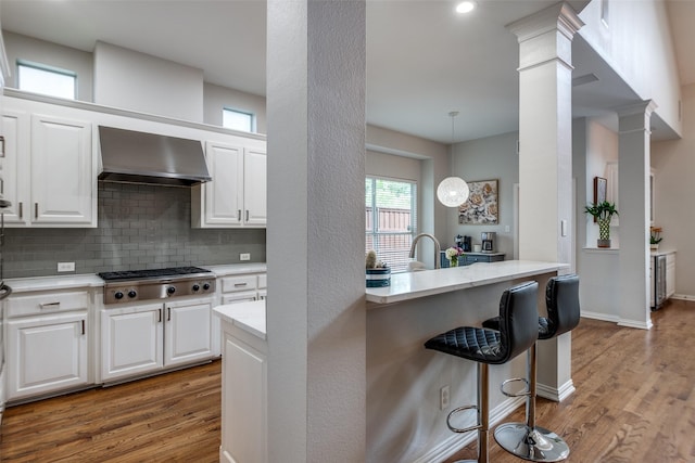 5001 Stanford Ave, Dallas, TX 75209 - kitchen with stainless steel gas cooktop, wall chimney range hood, wood finished floors, a breakfast bar area, and recessed lighting