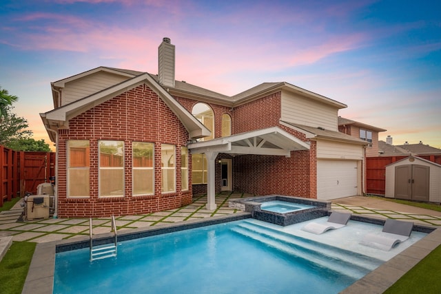 9772 Hickory St, Frisco, TX 75035 - back of property at dusk with brick siding, a chimney, a garage, a pool with connected hot tub, and a patio area