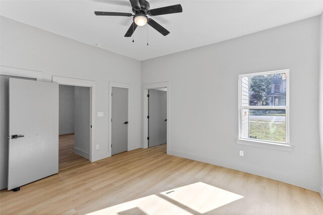 511 W Munson St, Denison, TX 75020 - unfurnished bedroom with wood finished floors, multiple closets, baseboards, and ceiling fan