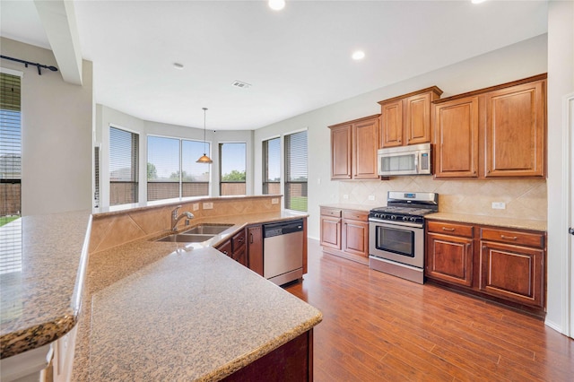 5125 Sugarberry Dr, Mckinney, TX 75071 - kitchen featuring appliances with stainless steel finishes, a sink, dark wood-style flooring, recessed lighting, and brown cabinetry